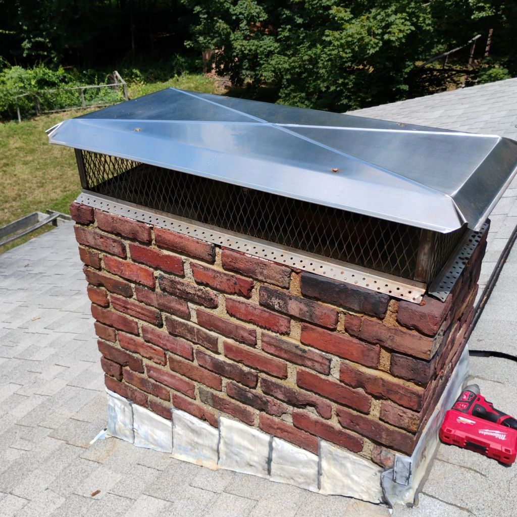Brick chimney with a metal cap after chimney and fireplace service