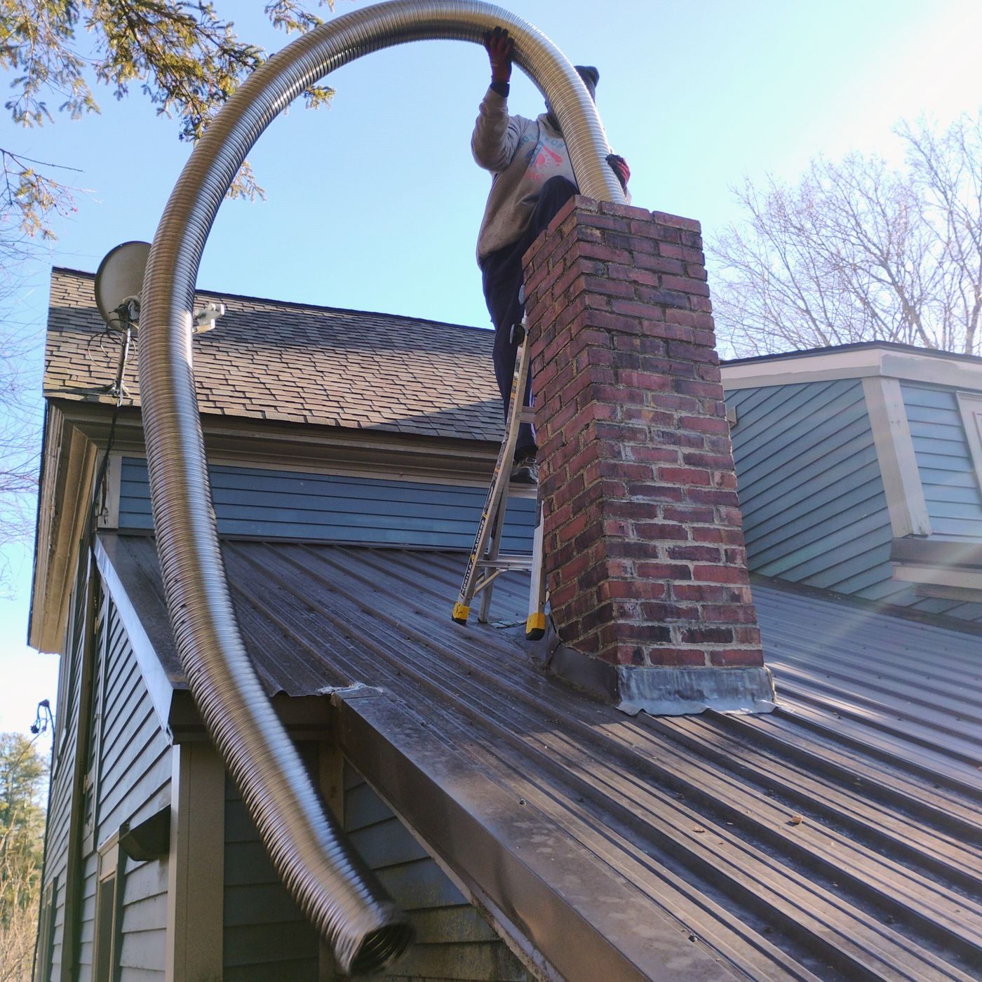Flexible metal chimney liner being installed in a residential brick chimney