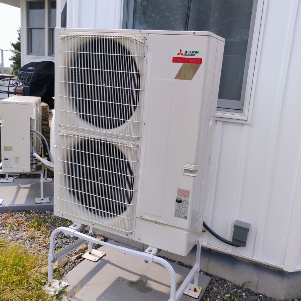 Mitsubishi residential heat pump outdoor unit professionally installed beside a home
